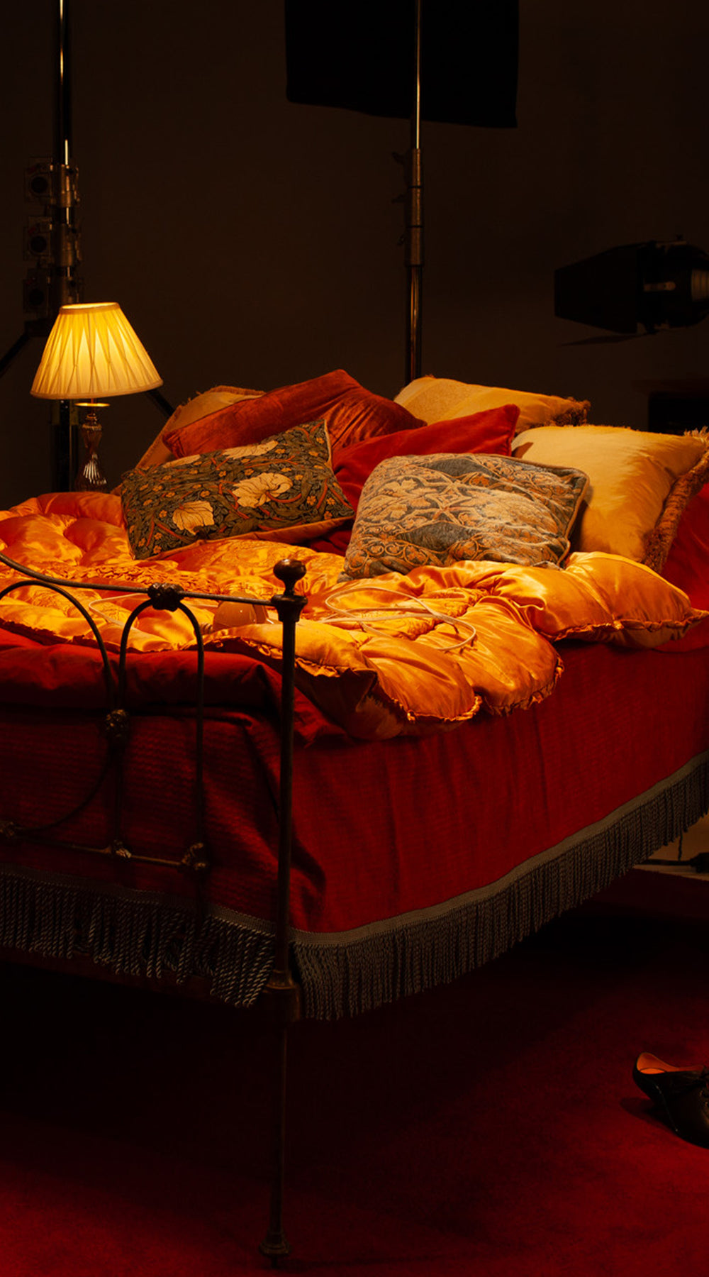 Bed with decorative pillows and a lamp in a dimly lit room